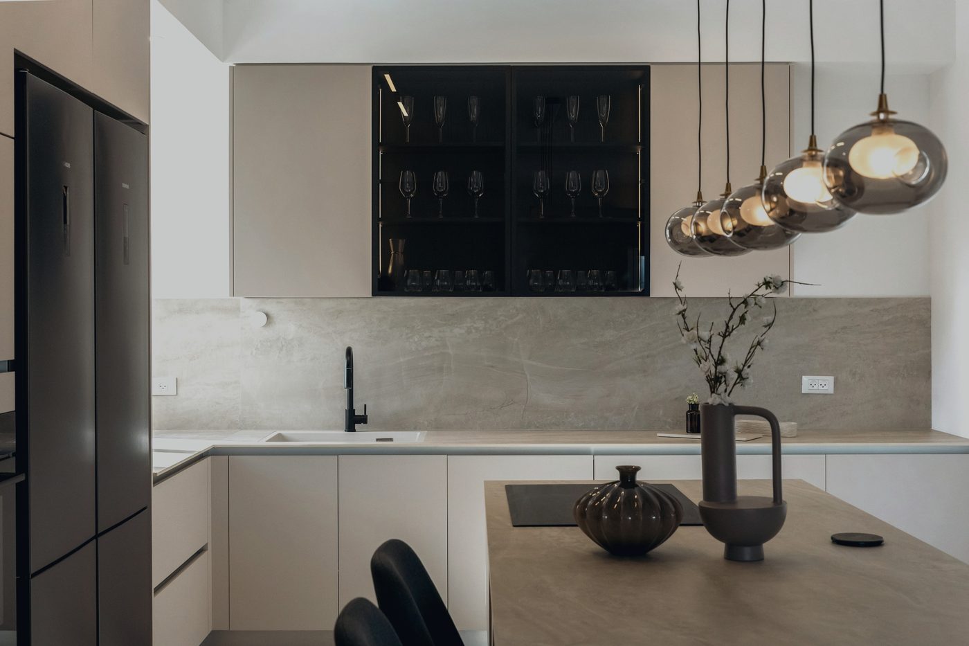 Modern kitchen lit by a row of pendant lights above the island bench